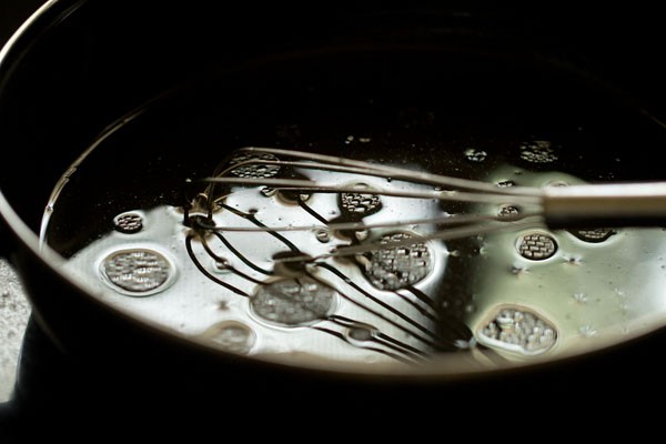 Whisk mixing liquid ingredients for muffin recipe in bowl.