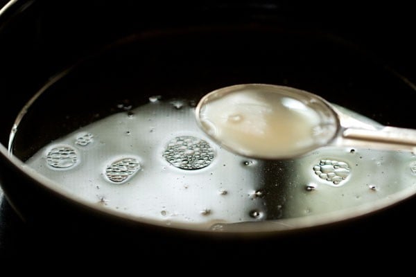 Vinegar in teaspoon measurer being added to liquid mixture in bowl.