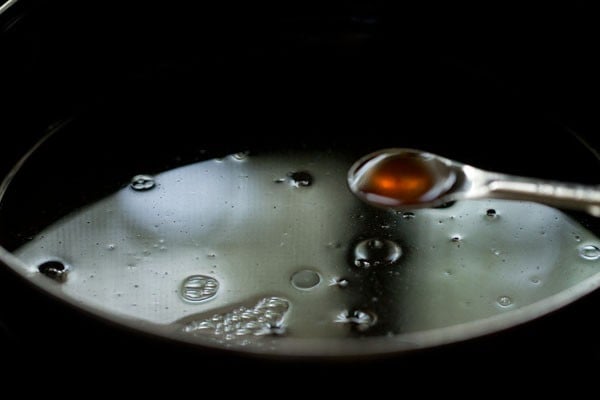 Vanilla extract in teaspoon measurer being added to liquid mixture in bowl.