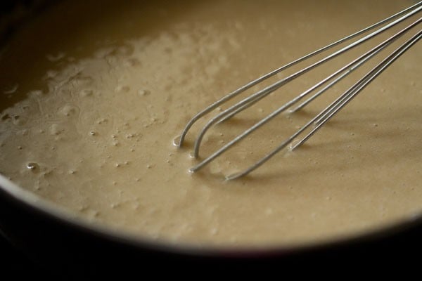 Whisk mixing smooth muffin batter in bowl.