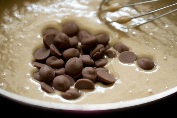 Chocolate chips added to muffin batter in bowl.