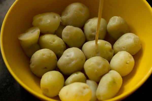 pricking steamed and peeled baby potatoes. 