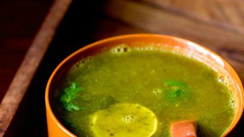 lemon rasam served in a brown colored bowl with a spoon inside and text layover.