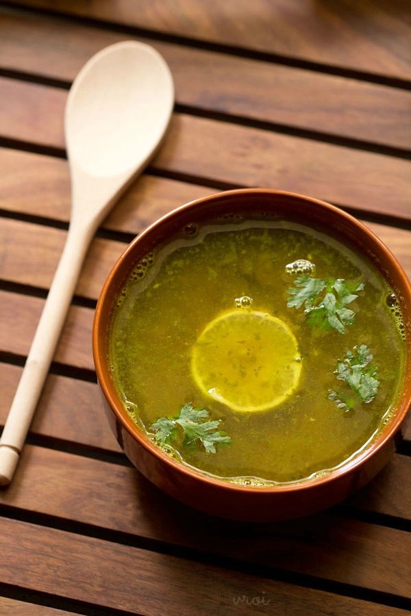 lemon rasam garnished with coriander leaves and served in a bowl. 