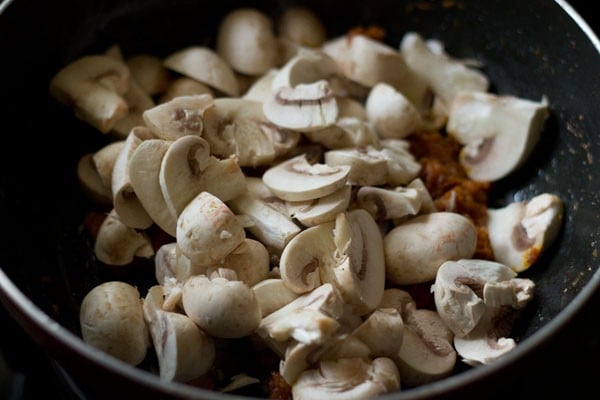 chopped mushrooms added to onion tomato masala in the pan