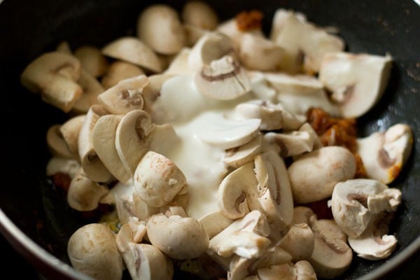 whisked curd added to mushroom masala mixture in the pan