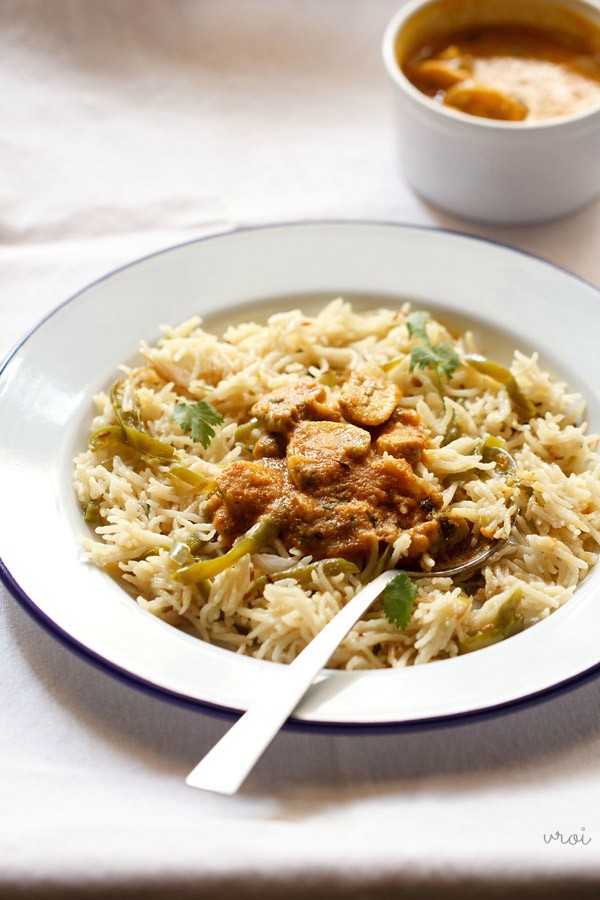 mushroom masala served on a bed of capsicum rice in a white plate