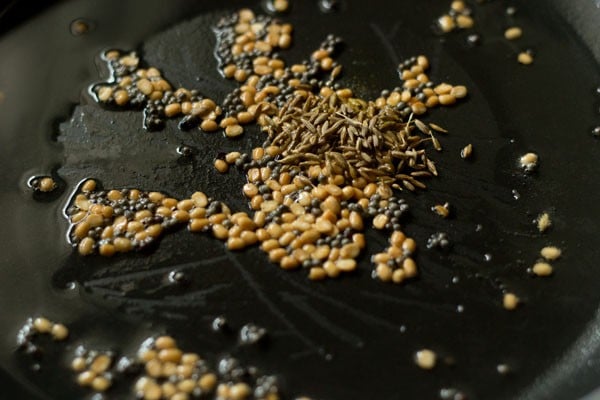 cumin seeds added in the pan for making raw banana sabzi. 