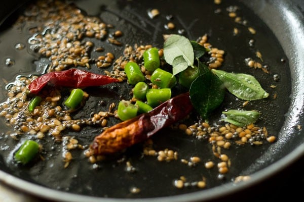 dried red chilies, asafoetida and curry leaves added in the pan for making raw banana sabzi. 