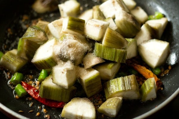 Make raw banana sabzi by dicing raw banana and adding salt in the pan. 