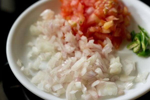 chopped onions, tomatoes, green chillies on a white plate.