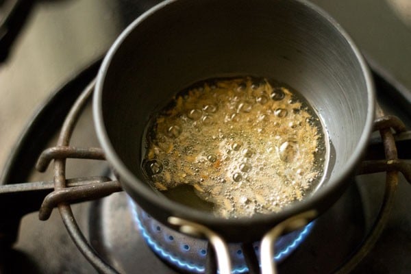 cumin seeds being fried in oil to make tadka for green gram curry.