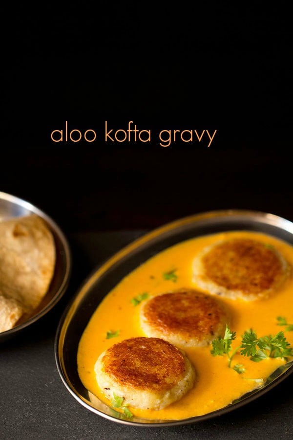 aloo kofta garnished with coriander sprig and served in a steel bowl with text layover.