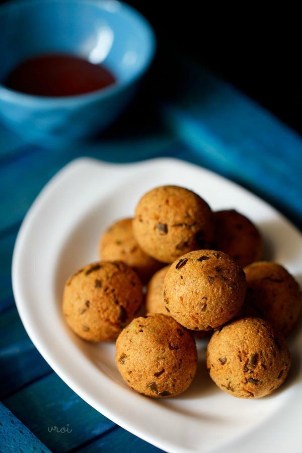 pile of Indian fried potato and cheese balls on a white serving plate on a blue cloth