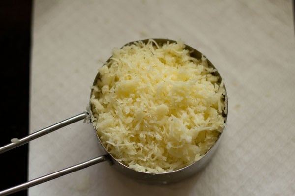 grated cheese in a silver half cup measure