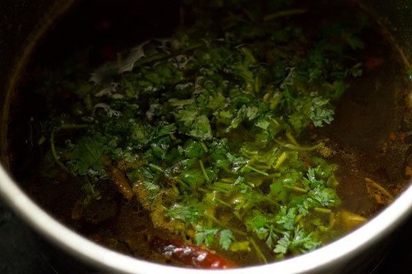 chopped coriander leaves added to cooked garlic rasam. 