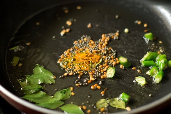 curry leaves, chopped green chilies, asafoetida and turmeric powder added to pan. 