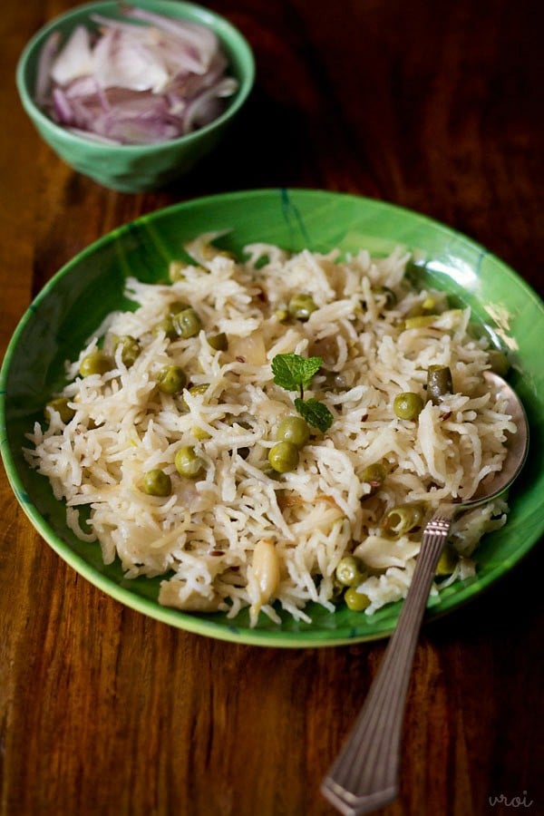 coconut milk rice or thengai paal sadam served in a green plate with a side of onion salad in a green bowl.