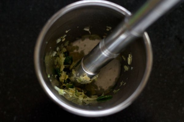crushing ginger, garlic cloves, green chili to make paste