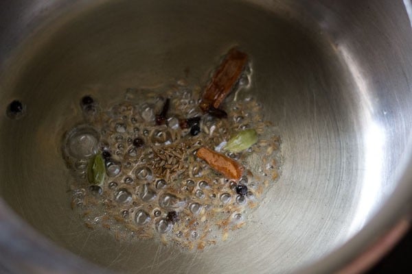 sautéing spices in a pressure cooker - cloves, green cardamoms, cinnamon, mace, cumin seeds