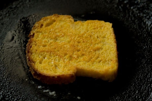 flipping the bread slice and toasting the other side. 