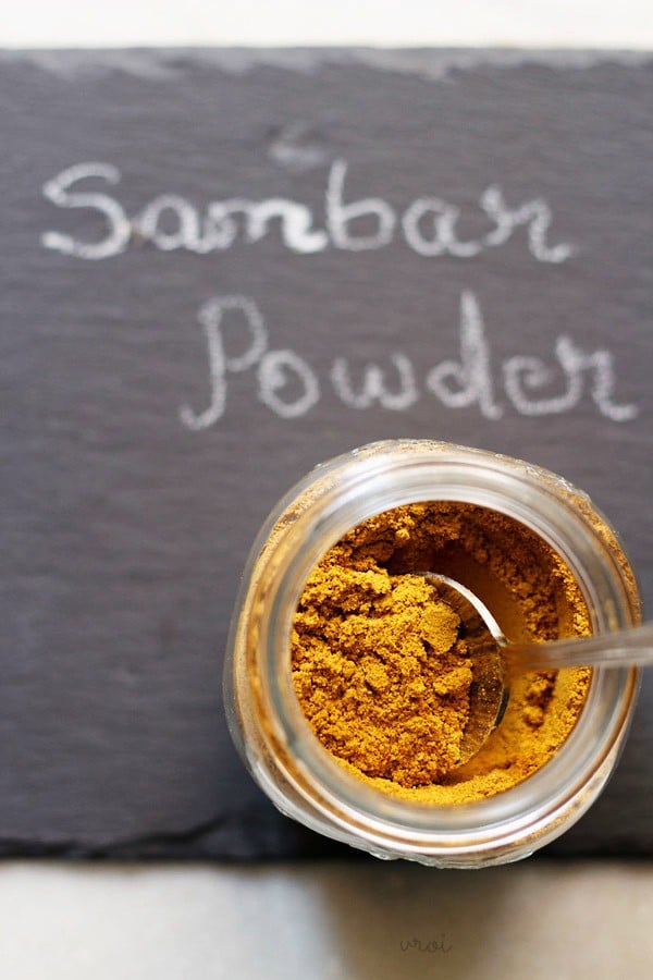 sambar podi in a glass jar with a spoon in it