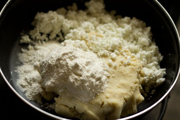 all-purpose flour and grated paneer added to mashed khoya in a bowl for kala jamun recipe. 