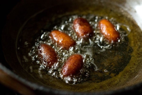 turning jamuns in the oil to get them evenly browned and dark.