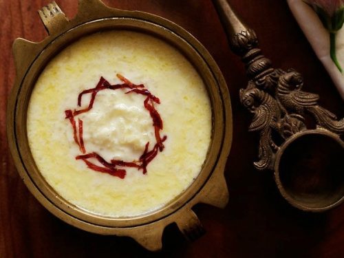 paal payasam garnished with dried rose petal chiffonade in a brass bowl with text layovers.
