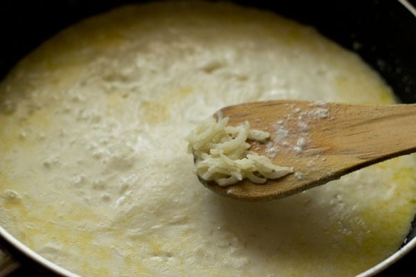 cooked rice grains on a wooden spatula. 