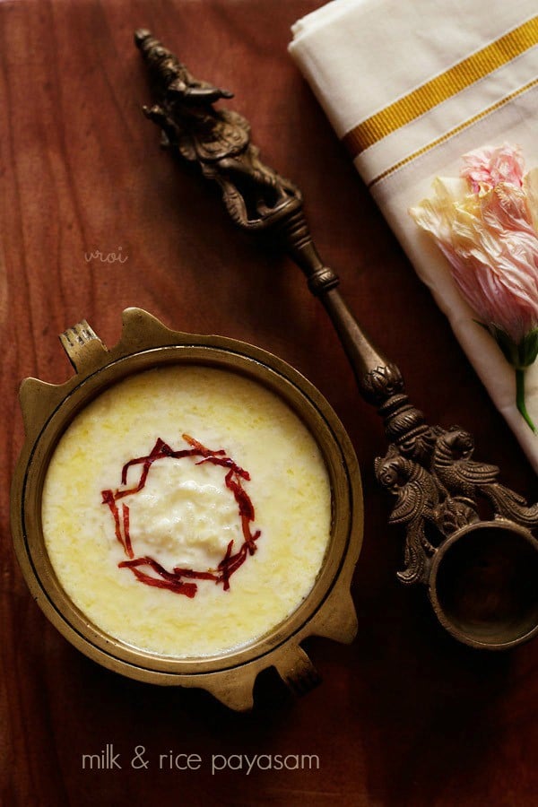paal payasam garnished with dried rose petal chiffonade in a brass bowl with text layover. 