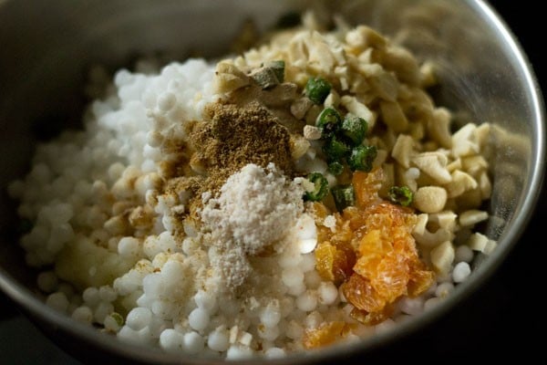 spices and sabudana added to mashed potatoes in a bowl