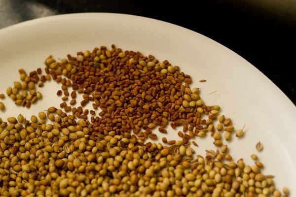 fenugreek seeds added to plate with other toasted spices for making sambar masala