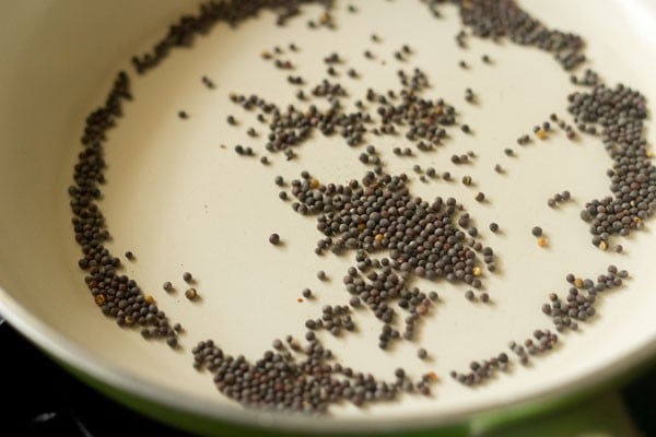 rai (black mustard seeds) in a dry pan