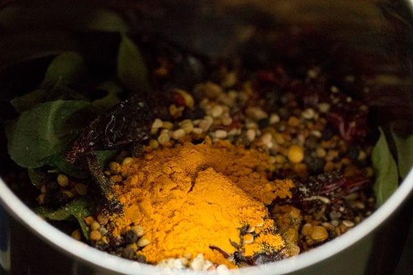 whole spices and turmeric in a grinder jar