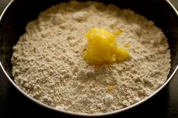 whole wheat flour and softened ghee added in a mixing bowl for making shakkarpare. 
