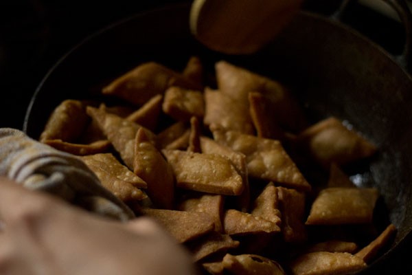 tossing to coat the shakkarpara well with the sugar syrup. 