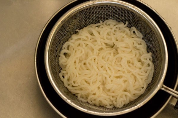 noodles draining in a mesh strainer for making veggie spring rolls recipe