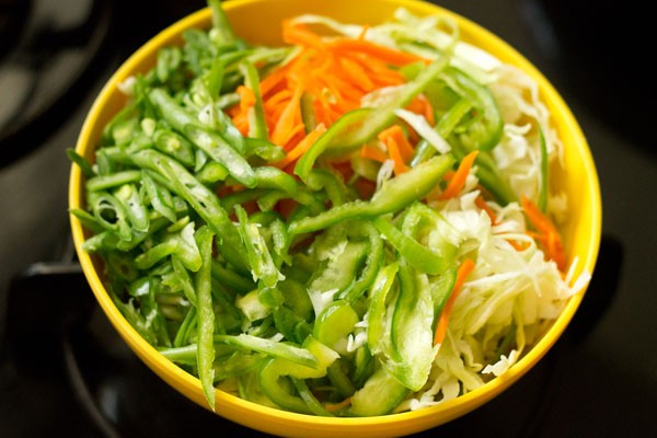 yellow bowl of an assortment of veggies for vegan spring rolls recipe
