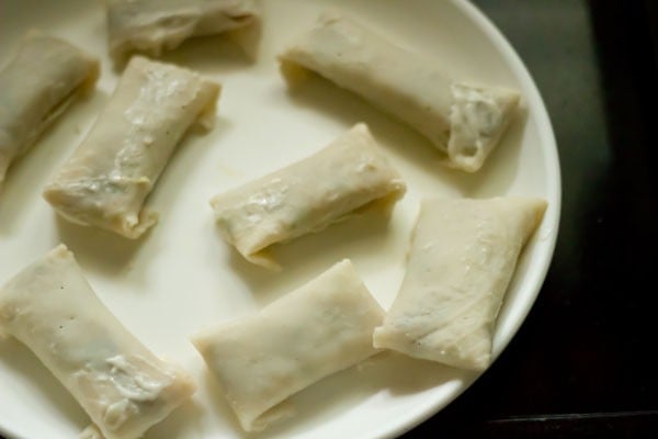plate of rolled spring rolls on a white plate prior to frying