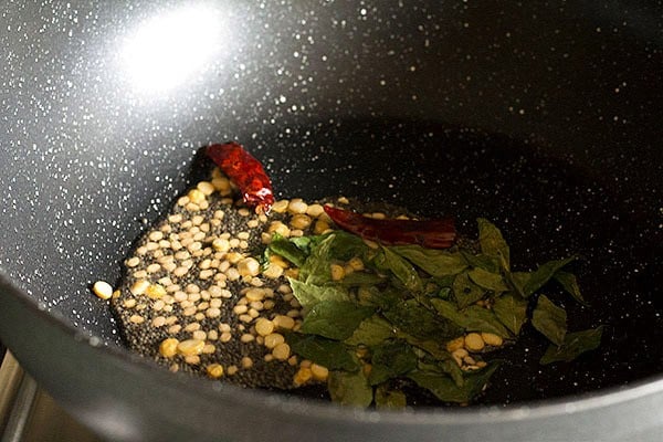 mustard seeds, chana dal, urad dal, curry leaves, finely chopped green chili and halved dried red chili added to hot oil in pan.
