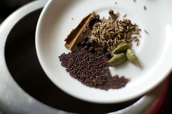 adding whole spices to hot oil in pressure cooker. 