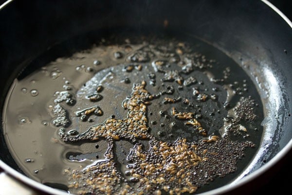 sauteing cumin seeds in oil in the pan