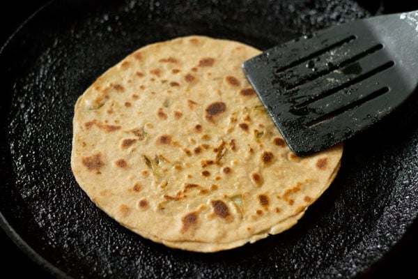 pressing cabbage paratha edges with spatula