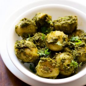 chutney wale aloo adornado con hojas de cilantro y servido en un tazón blanco sobre un plato blanco con una escala de texto.