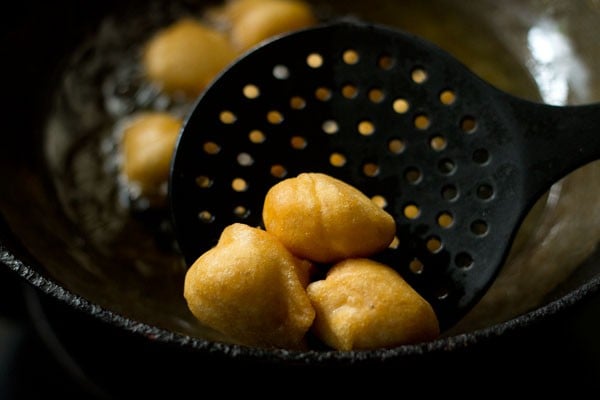 removing evenly fried bhallas with a slotted spoon. 