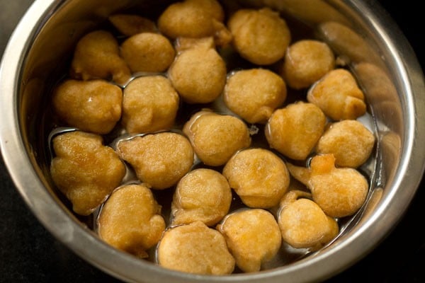 fried bhallas added to water in a bowl. 