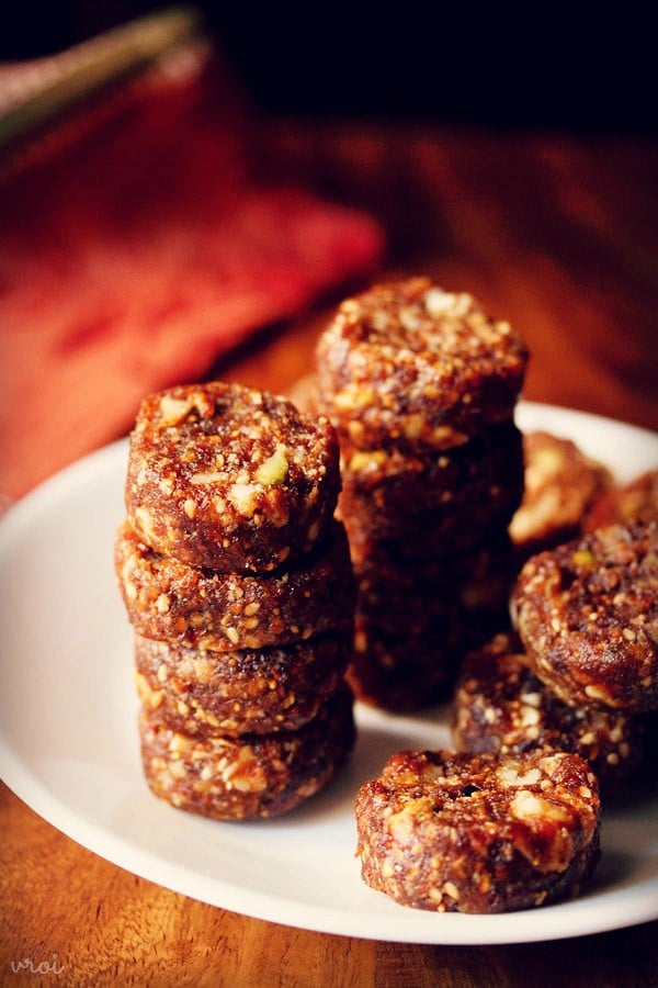 stacks of dry fruit barfi or date rolls on a white plate.