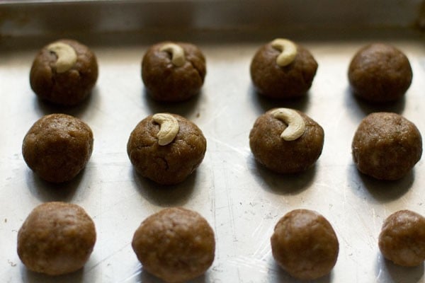 cashews placed on each dough ball on the tray. 