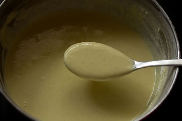 spoon showing thinner consistency of jalebi batter after fermentation